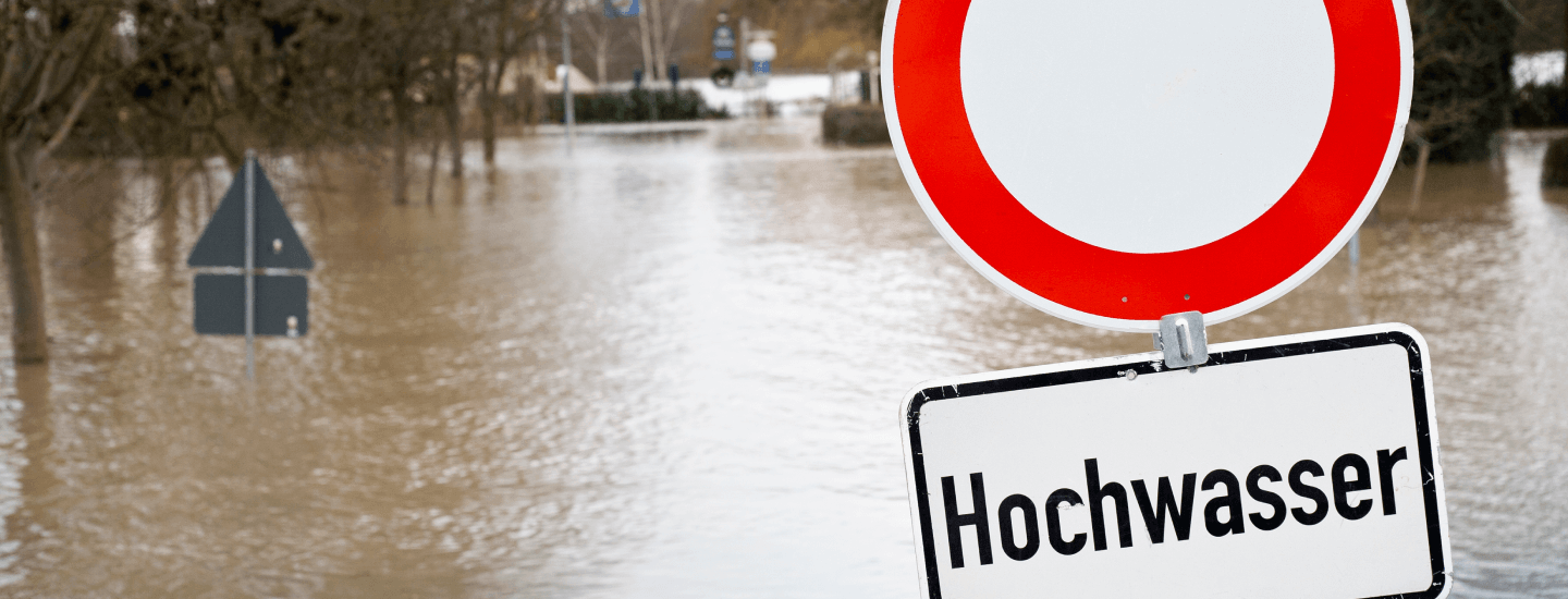 Überflutete Straße mit Verkehrszeichen "Hochwasser".