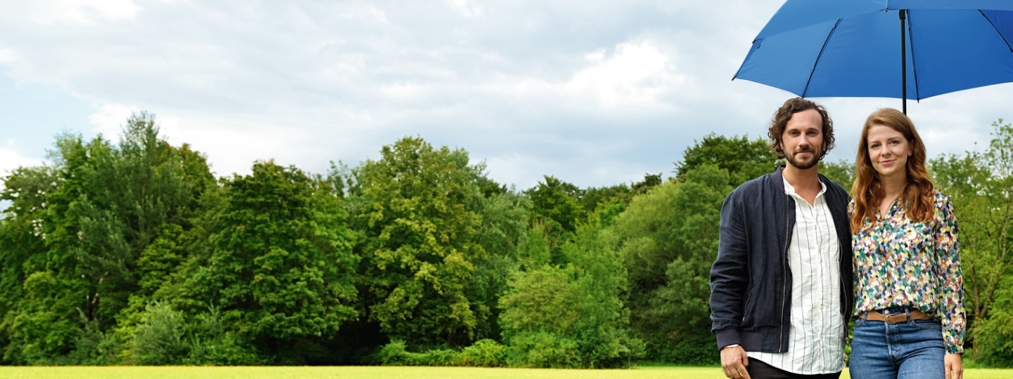 Frau und Mann im Park unter einem blauen Schirm 