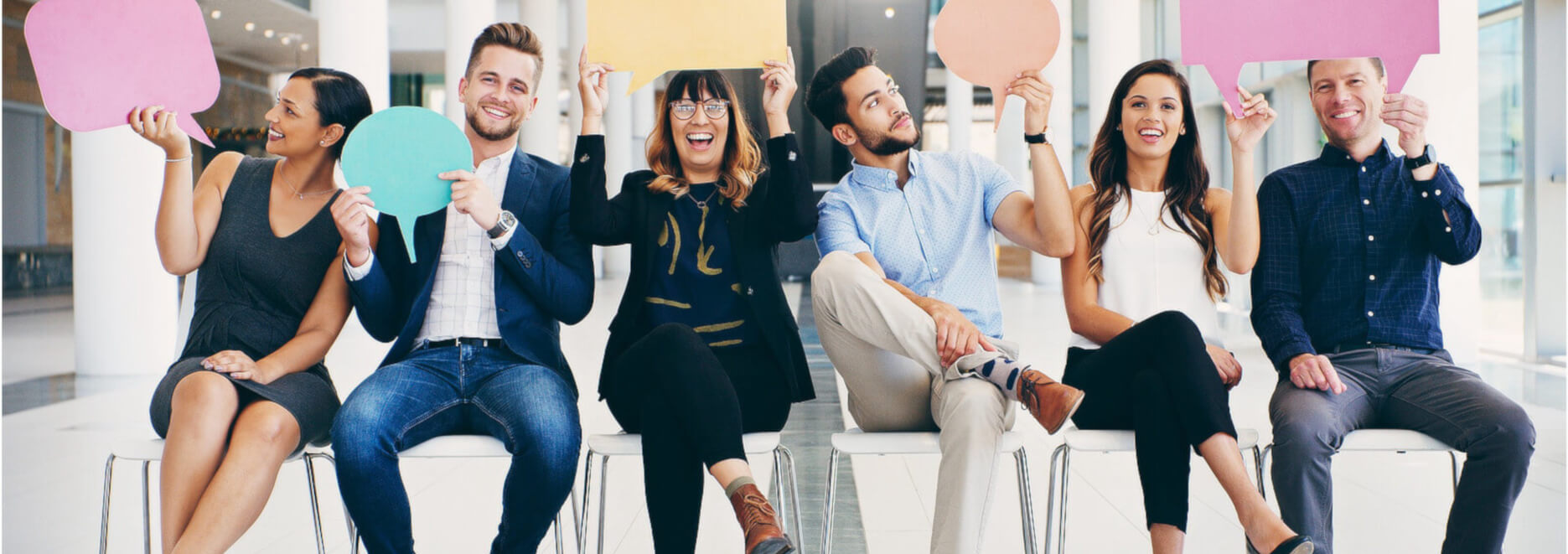 Eine Gruppe von jungen Menschen sitzen lachend auf Stühlen