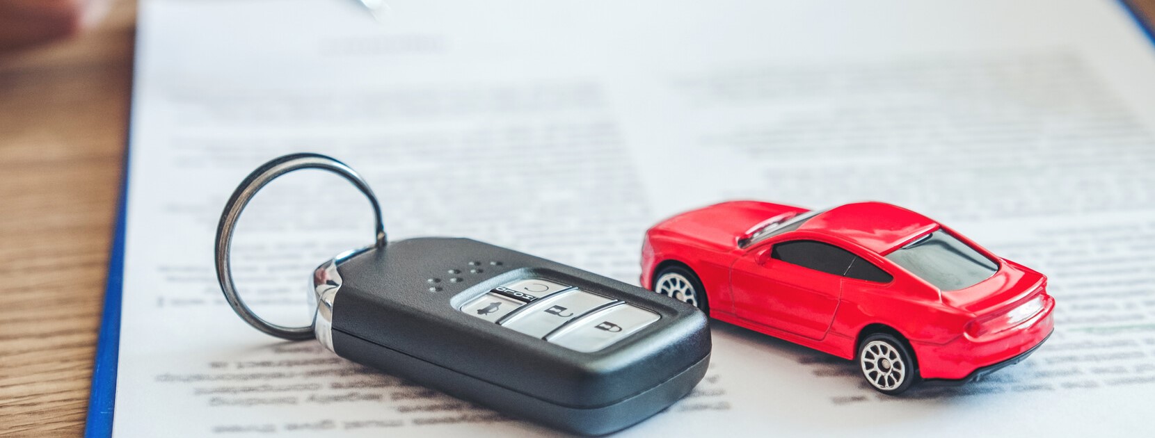Autoschlüssel und Spielzeugauto liegen auf einem KFZ-Vertrag.
