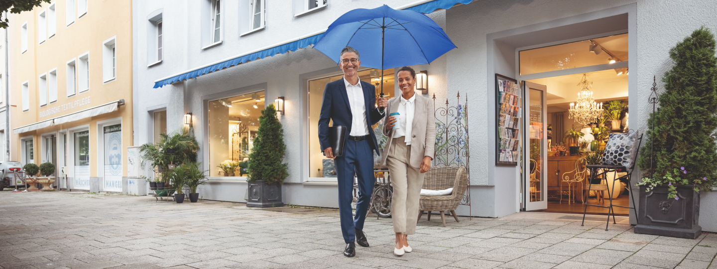 Ehepaar läuft mit blauem Schirm von Geschäft weg