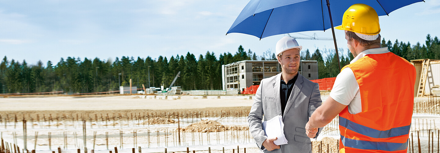 Zwei Männer mit Helmen unterhalten sich unter dem blauen Schutzschirm