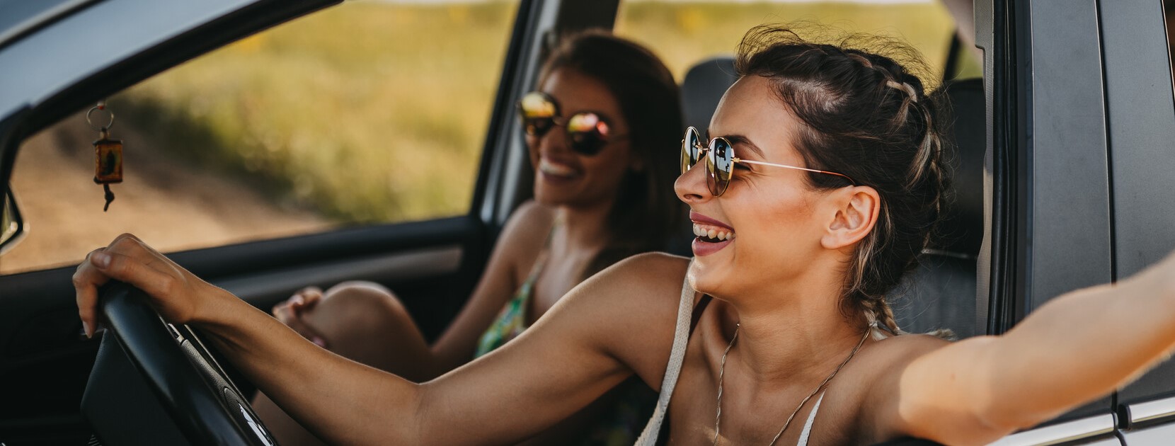 Lachende Frauen im Auto auf einem Roadtrip.