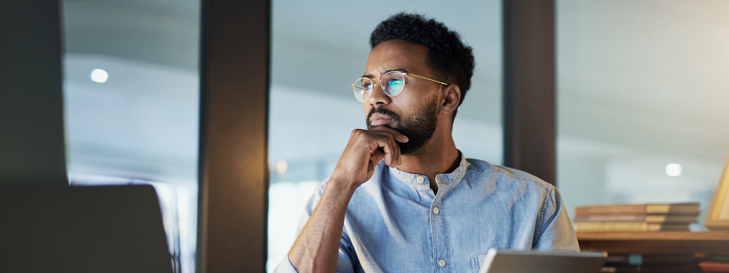 Mann sitzt an einem Schreibtisch und überlegt