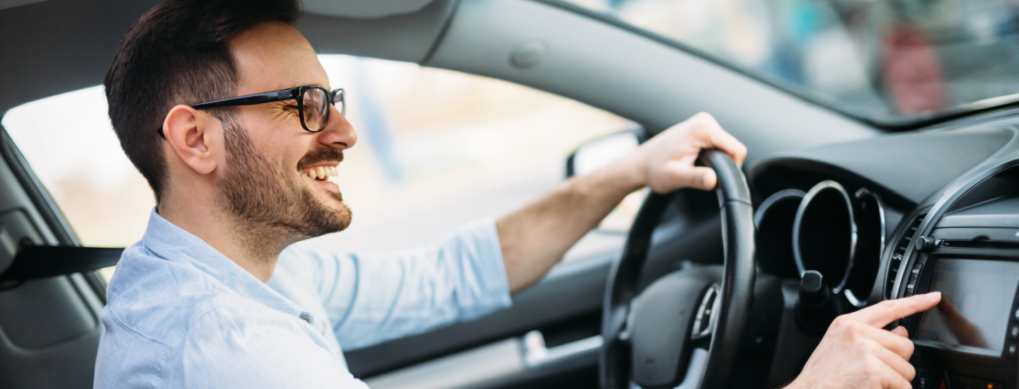 Mann sitzt lachend am Steuer.