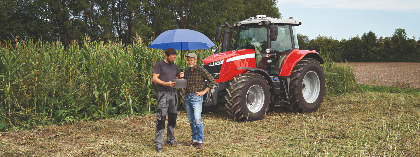 Zwei Landwirte stehen auf dem Feld vor einem Traktor