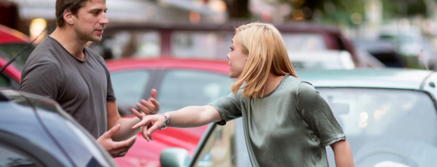 Eine Frau und ein Mann diskutieren bei einem Autounfall.