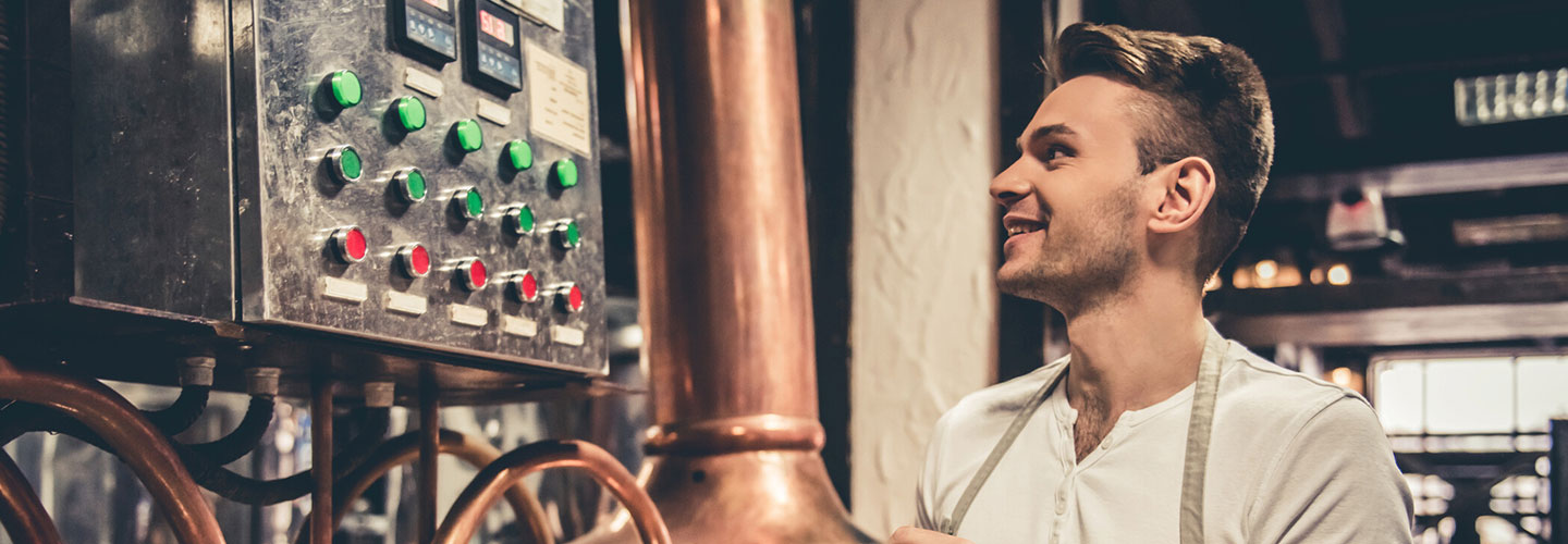 Mann in einer Halle vor einem Gerät mit grünen und roten Knöpfen