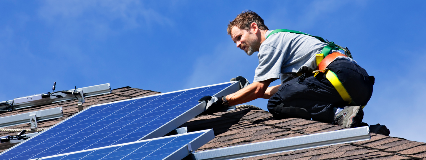 Mann auf Dach montiert Panele einer PV Anlage