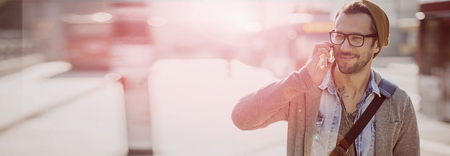 Mann mit Mütze und Brille telefoniert im Freien
