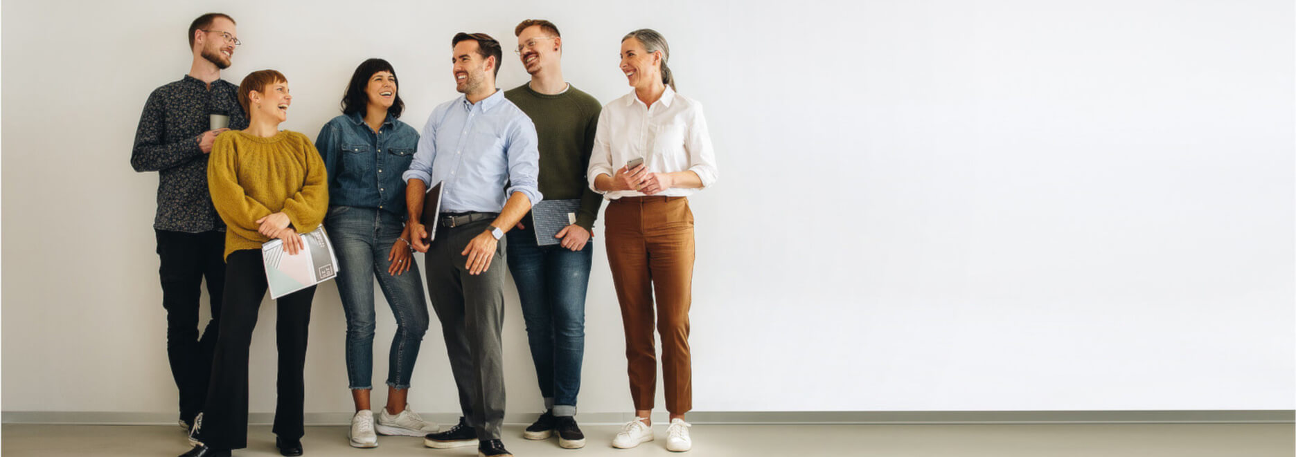 Eine Gruppe von jungen Menschen stehen lächelnd vor einer Wand