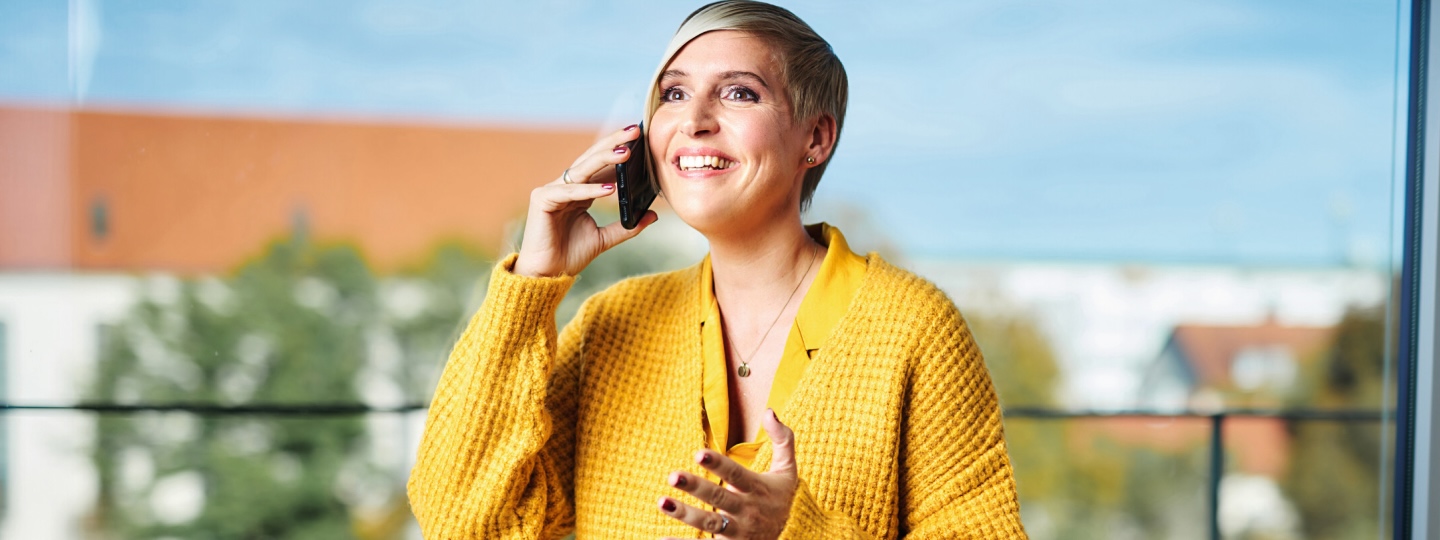 Frau in gelber Kleidung am Telefonieren