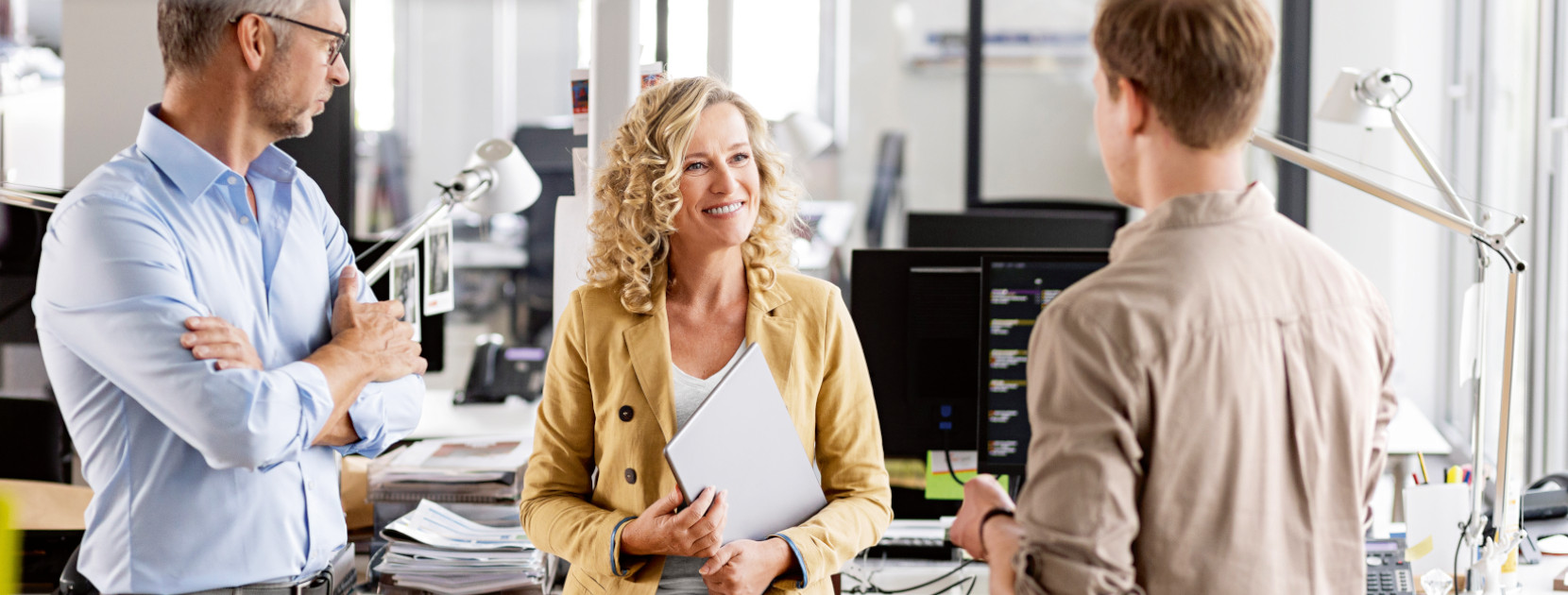 Drei Personen im Büro führen ein Gespräch.