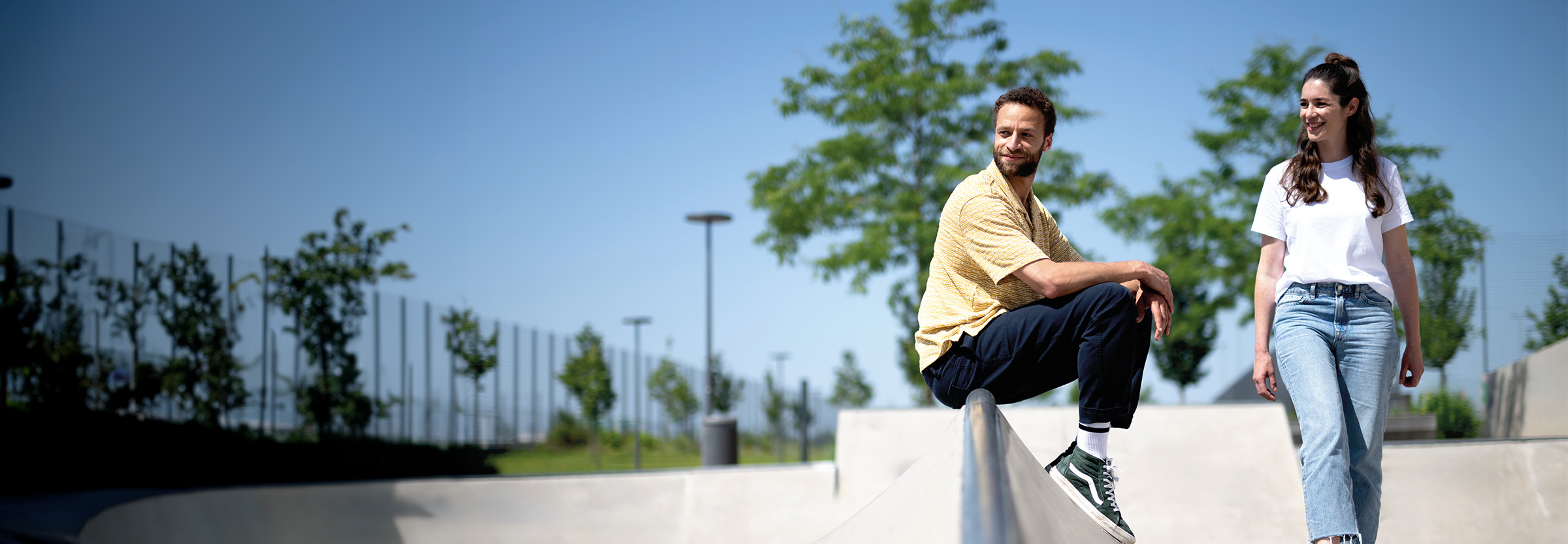 Junge Frau und junger Mann entspannen in einem von Grün umsäumten Gelände