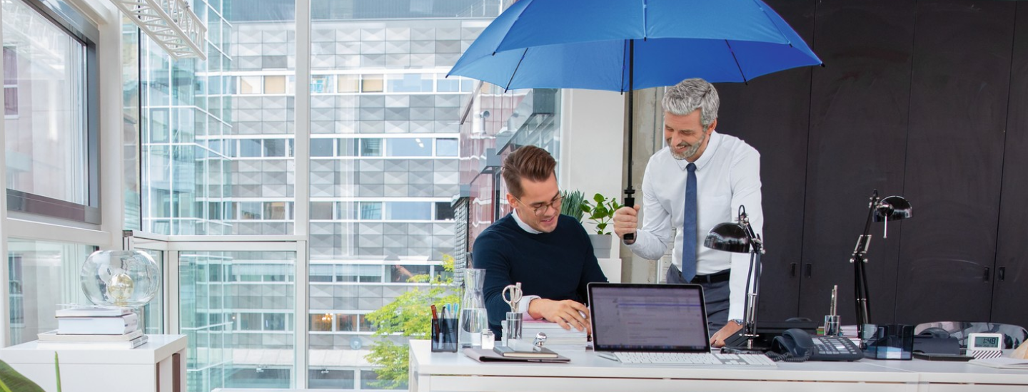 Zwei Männern unter einem blauen Schirm in einem Bürogebäude