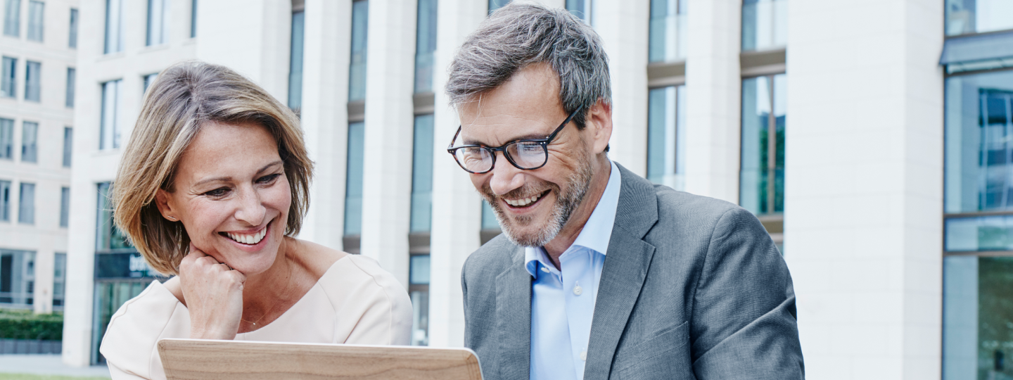 Mann und Frau blicken auf einen Laptop