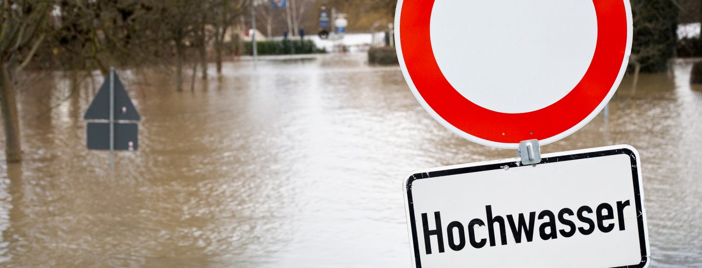 Überflutete Straße mit Verkehrszeichen "Hochwasser".